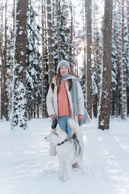 Woman Standing On Snow Covered Ground With A Siberian Husky