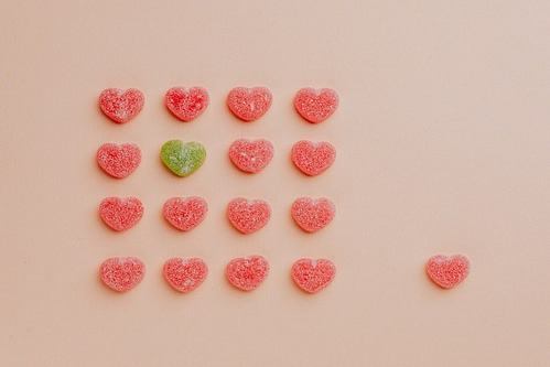 Top view of delicious sprinkled jelly sweets composed in lines with one candy aside on pink backdrop