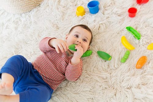 View from above of baby chewing on toys