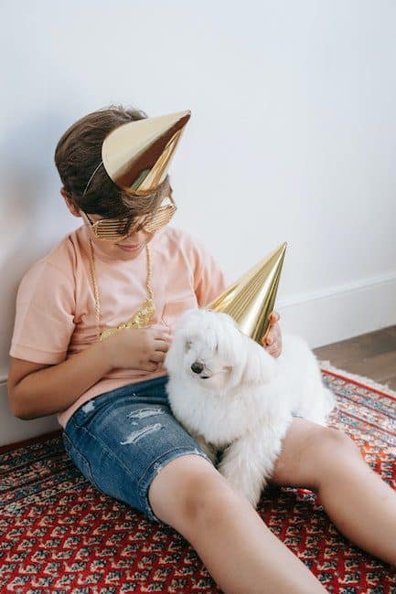 Boy in a Salmon Shirt Putting a Party Hat on His Dog's Head