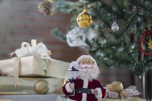 Santa Claus toy near gift boxes under Christmas tree