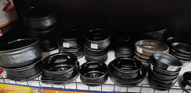 Melaware cookwares - a rack with a bunch of black pots